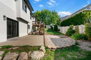 Fenced backyard featuring a patio, stairs, and a deck with mountain view