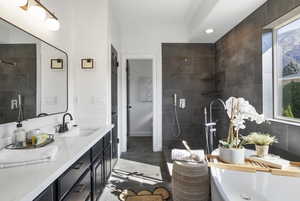 Bathroom with a walk in shower, double vanity, dark tile patterned floors, and recessed lighting