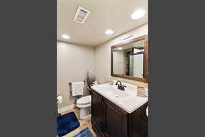 Bathroom with vanity, light tile patterned floors, recessed lighting, and a textured wall