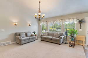 Carpeted living room featuring a chandelier and baseboards