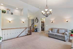Living area featuring carpet flooring, a chandelier, and high vaulted ceiling