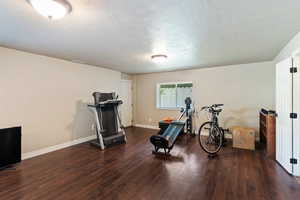 Workout area featuring dark wood-style flooring and a textured ceiling