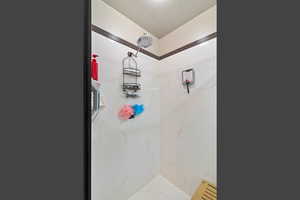Bathroom featuring a marble finish shower