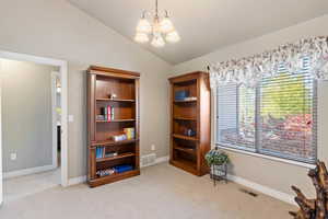 Living area featuring light carpet, a chandelier, and lofted ceiling