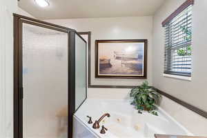 Full bath with a shower stall and a jetted tub