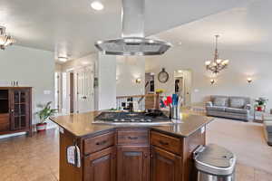 Kitchen featuring decorative light fixtures, island exhaust hood, dark stone counters, open floor plan, and lofted ceiling