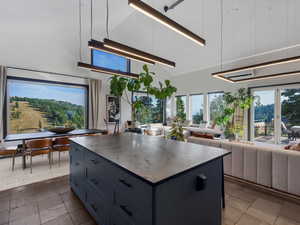 Kitchen with a center island, a towering ceiling, open floor plan, healthy amount of natural light, and decorative light fixtures