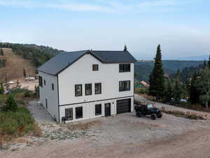 Modern farmhouse style home featuring dirt driveway, a metal roof, a view of trees, and a garage