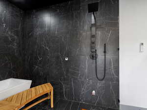 Full bath featuring a marble finish shower and tile walls