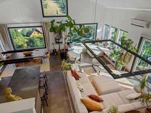 Living room featuring a high ceiling and a wall mounted air conditioner