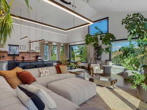 Living area with wood finished floors, high vaulted ceiling, and plenty of natural light