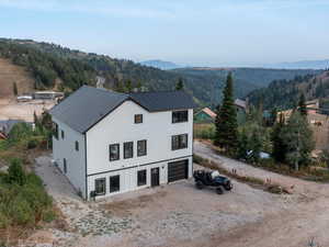 Aerial view of property and surrounding area with a forest and mountains