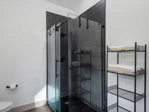 Bathroom featuring toilet and a marble finish shower