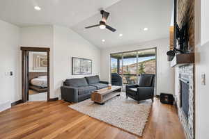 Living area with lofted ceiling, light wood-style floors, recessed lighting, and a stone fireplace