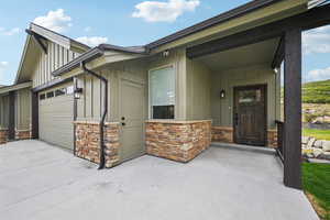 Entrance to property with stone siding, board and batten siding, a garage, and driveway
