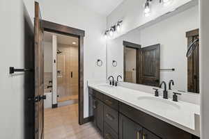 Bathroom with double vanity, light tile patterned flooring, and a stall shower