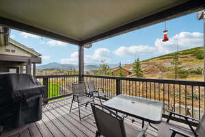 Wooden deck with outdoor dining area, area for grilling, and a mountain view