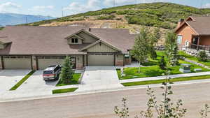 Craftsman inspired home featuring concrete driveway, a mountain view, stone siding, roof with shingles, and board and batten siding