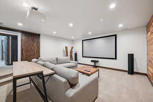 Home theater with a barn door, light colored carpet, and recessed lighting