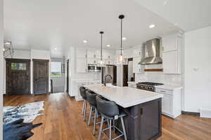Kitchen with white cabinets, a center island with sink, dark wood-style floors, and recessed lighting