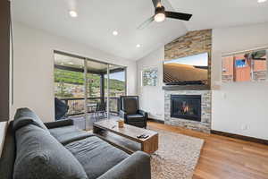 Living area featuring lofted ceiling, light wood-type flooring, a fireplace, recessed lighting, and ceiling fan