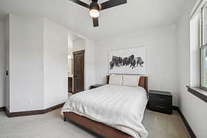 Carpeted bedroom featuring ensuite bathroom and ceiling fan