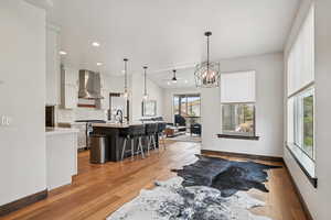 Kitchen featuring open floor plan, white cabinetry, pendant lighting, tasteful backsplash, and a chandelier