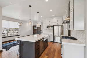 Kitchen featuring white cabinets, light stone counters, decorative light fixtures, light wood-type flooring, and recessed lighting