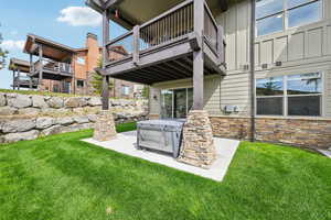 View of grassy yard with a hot tub, a patio, and a balcony