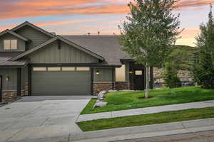 Craftsman inspired home with a shingled roof, board and batten siding, driveway, a garage, and stone siding