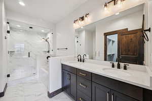 Bathroom with a marble finish shower, a bath, double vanity, light marble finish flooring, and recessed lighting