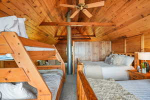 Bedroom with wood ceiling, carpet floors, wood walls, a ceiling fan, storage area and balcony access