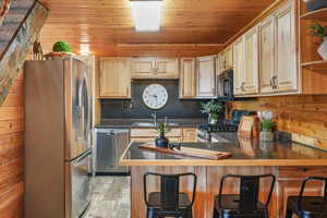 Kitchen featuring dark countertops, stainless steel appliances, and a kitchen bar