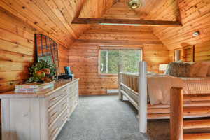 Carpeted bedroom featuring wood walls, ceiling fan and wood ceiling