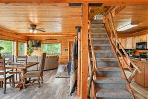 Stairway with wooden ceiling, wood-style LVP finished floors, ceiling fan, and wooden walls