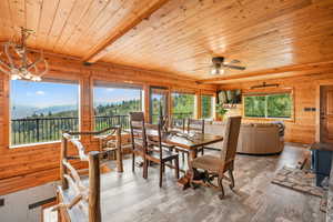 Dining area featuring wooden walls, a wooden ceiling with exposed beams, wood-style LVP finished floors, a wood stove, and a mountain/valley view