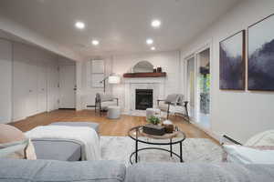 Living room with light wood-type flooring, a premium fireplace, recessed lighting, and a baseboard heating unit