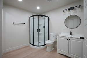 Bathroom with light wood finished floors, vanity, a shower stall, and recessed lighting