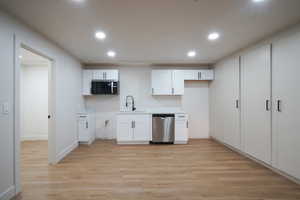 Kitchen with white cabinets, light wood finished floors, light countertops, recessed lighting, and stainless steel appliances