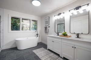 Bathroom featuring double vanity, a shower stall, a freestanding bath, dark tile patterned flooring, and a textured ceiling