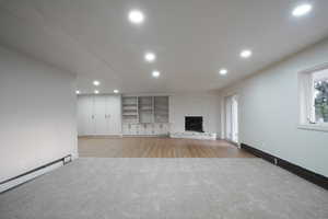 Unfurnished living room featuring healthy amount of natural light, light colored carpet, a stone fireplace, and recessed lighting