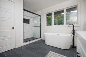 Bathroom with a marble finish shower, a soaking tub, a textured ceiling, and vanity