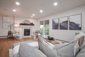 Living room featuring recessed lighting, light wood finished floors, a fireplace, and baseboard heating