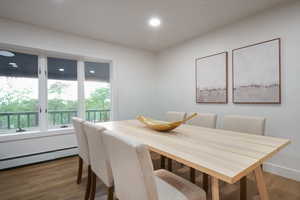 Dining room with wood finished floors, baseboard heating, and recessed lighting