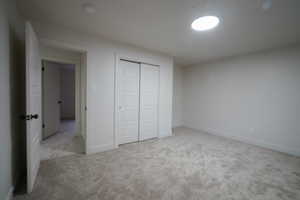Unfurnished bedroom with light colored carpet and a closet
