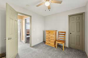 Carpeted bedroom with a ceiling fan and baseboards