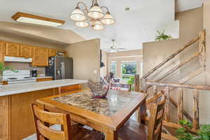 Kitchen featuring light countertops, a chandelier, white range with electric stovetop, stainless steel fridge, and pendant lighting