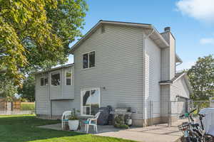 Rear view of house featuring a patio, a gate, and a chimney