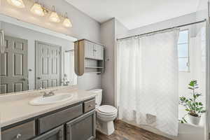 Full bath featuring dark wood-style flooring, vanity, and shower / bathtub combination with curtain