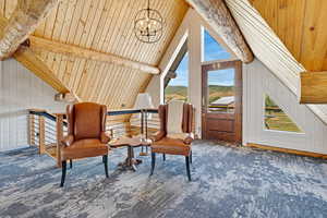 Sitting room featuring wood walls, carpet flooring, a chandelier, a wood ceiling with exposed beams, and high vaulted ceiling